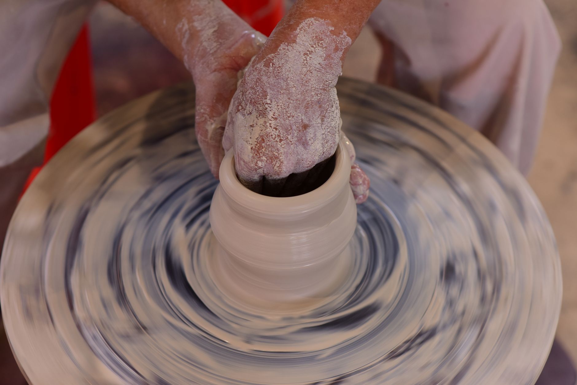 Hands shaping clay on a pottery wheel.
