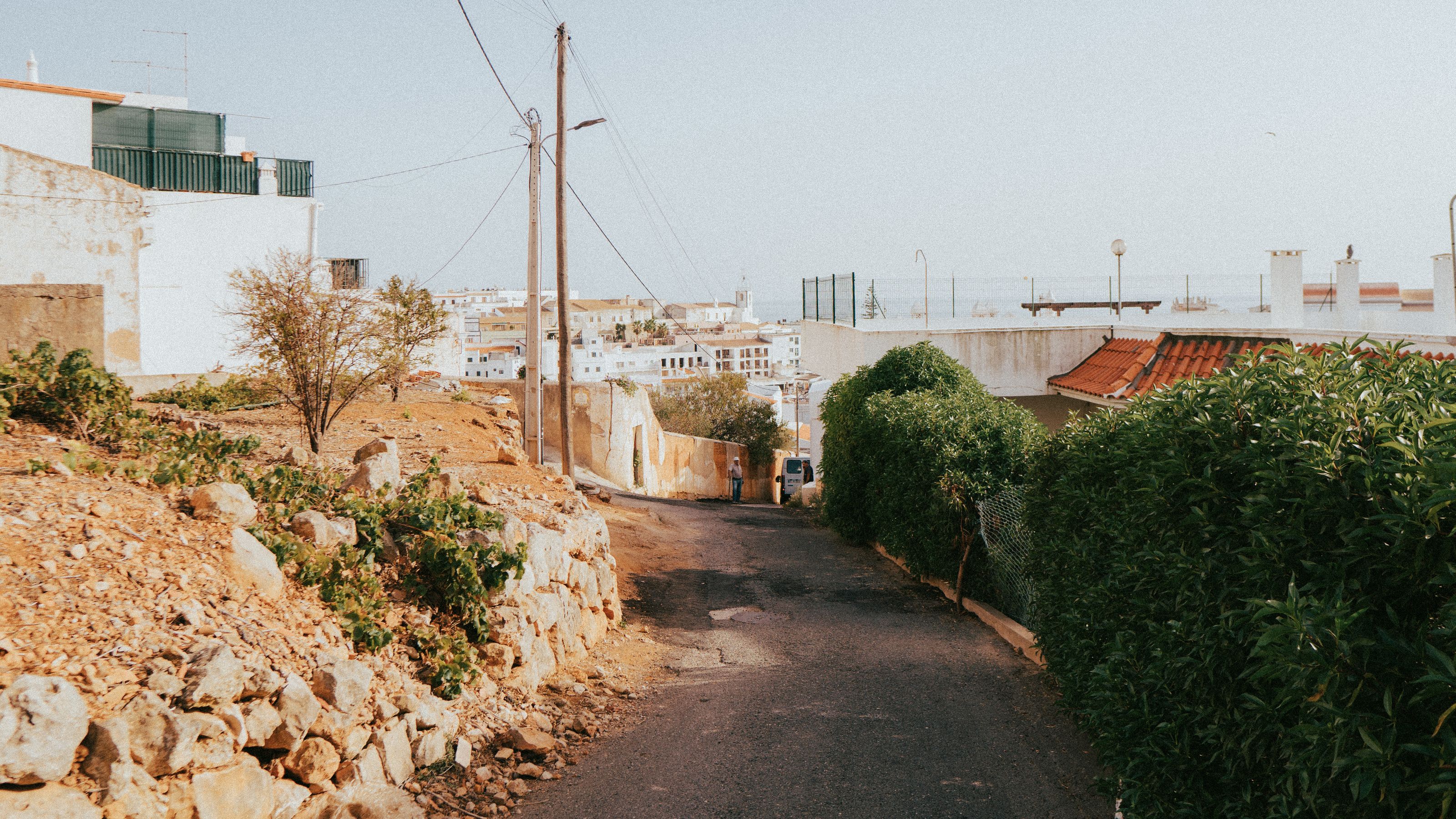 A sunlit narrow street in the Algarve with the sea at the end of it.